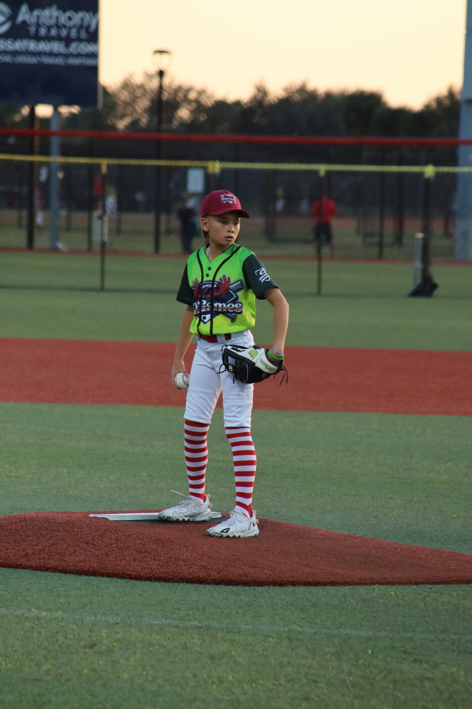 Pitcher on the mound at sunset in an Elf Games jersey with candy-striped socks.