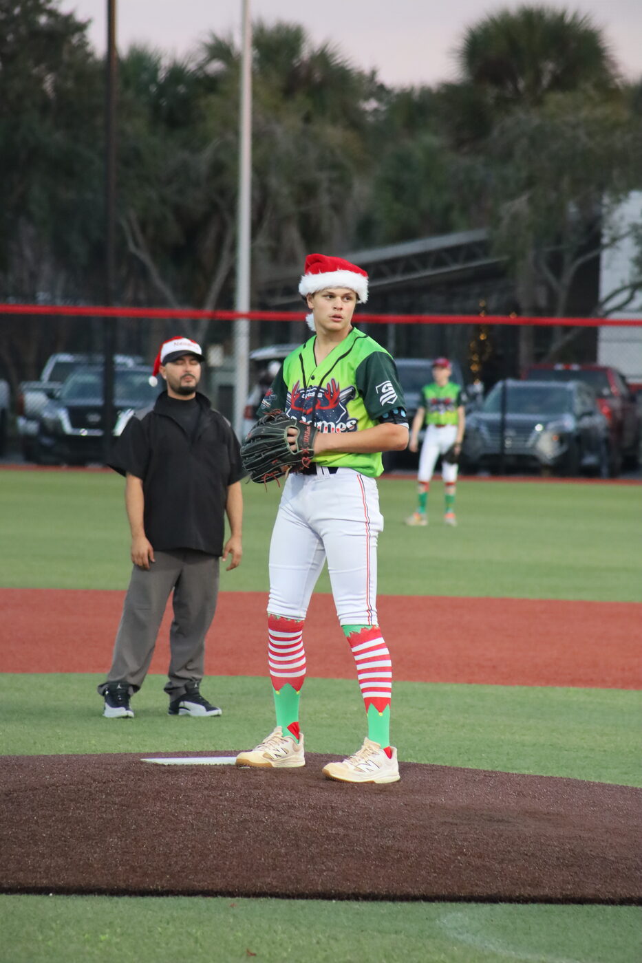 Elf Games pitcher in a Santa hat and candy-striped socks mid-windup.