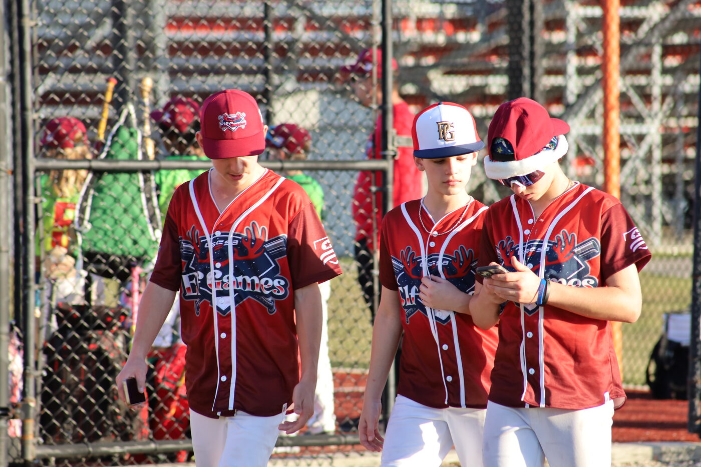 Three teammates in red Elf Games jerseys walking to the field together, one wearing a Santa hat.